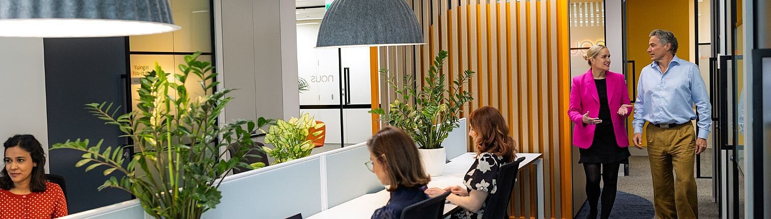Nous staff collaborating in a modern, plant-filled office space.