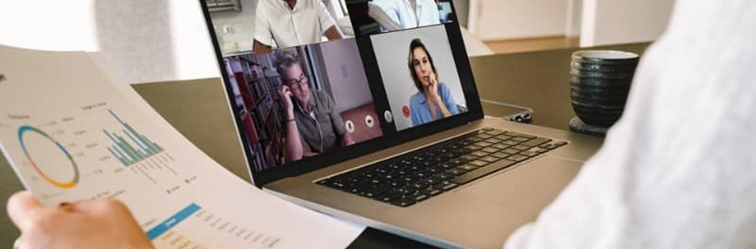 A person in a virtual meeting holding a sheet with data