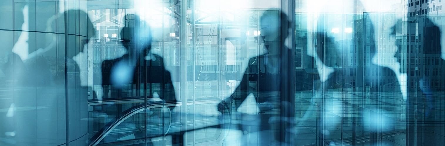 Businesspeople working as seen through cold blue glass.