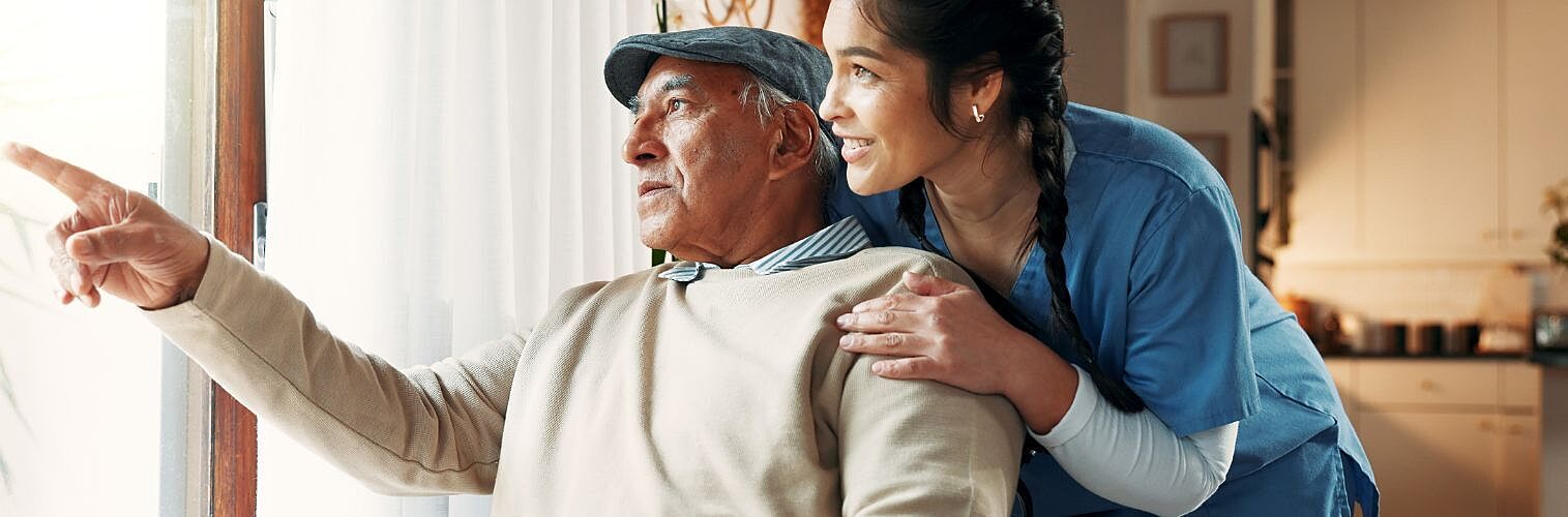 Old man and aged care worker looking out the window.