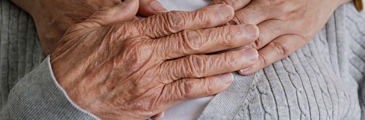 Young hands hugging an elderly person from behind.