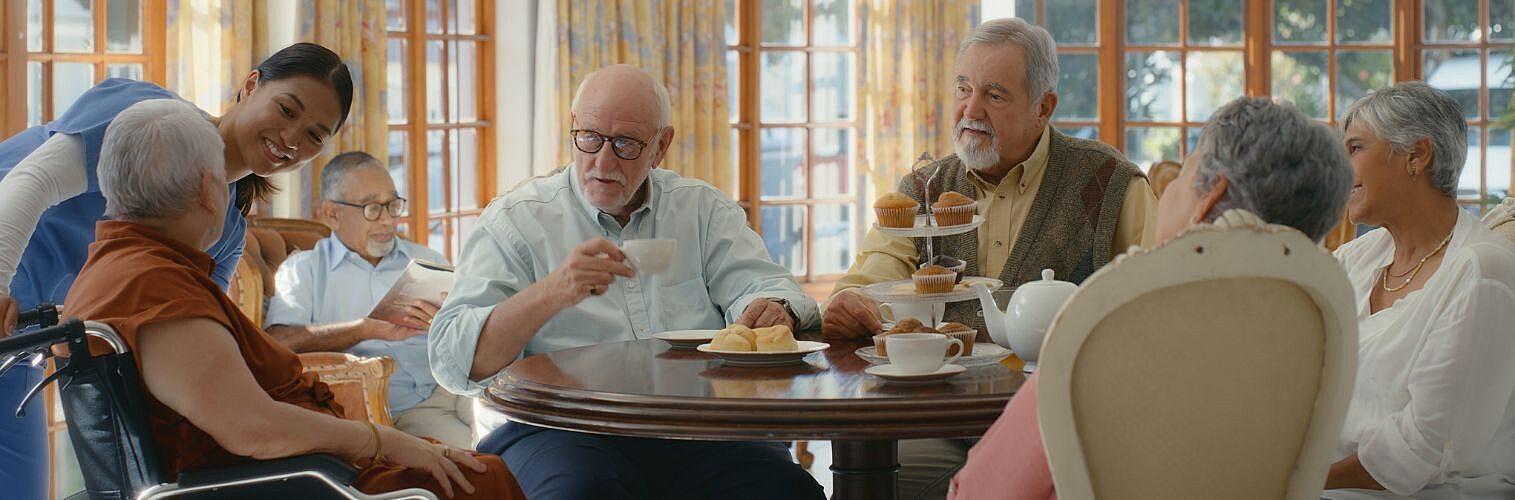 Patients chatting over coffee with a nurse in an old folk's home.