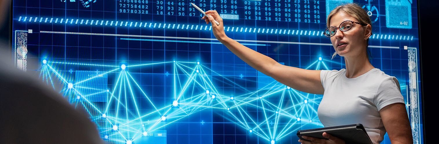 A female programmer confidently presents her investment analysis software to executives in a sleek office.