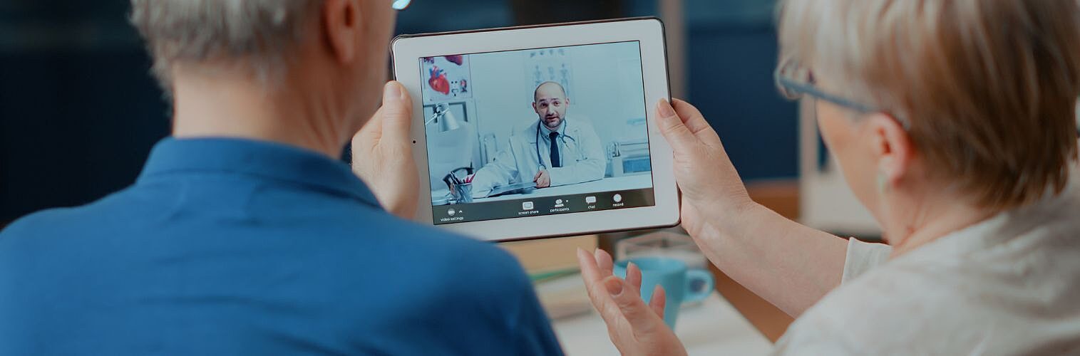 A senior couple consulting a doctor on a digital tablet.