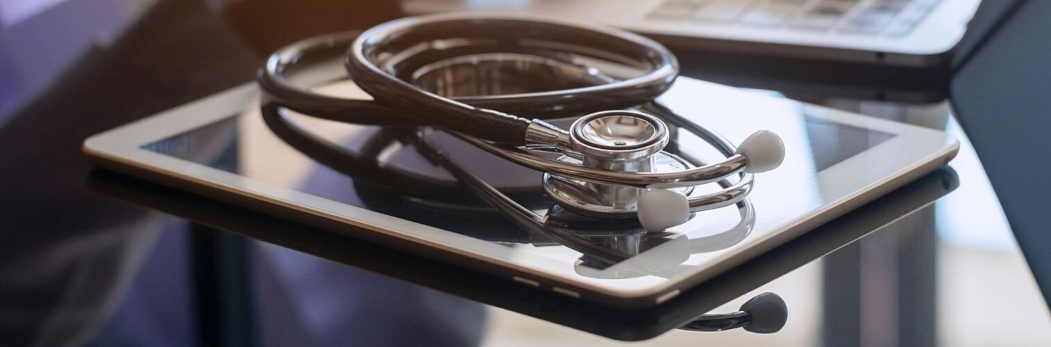 A digital tablet and medical stethoscope on an office desk.