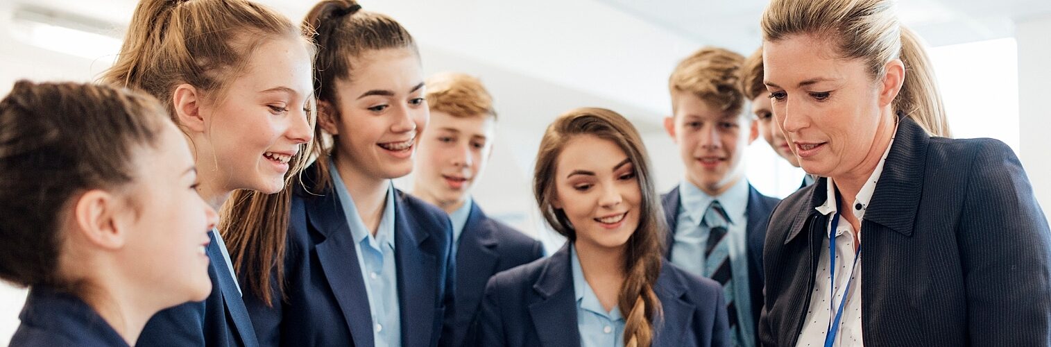 A female teacher talking to a group of students in a science room.