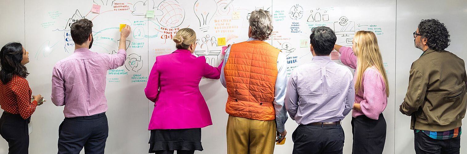 Nousers standing at a whiteboard.