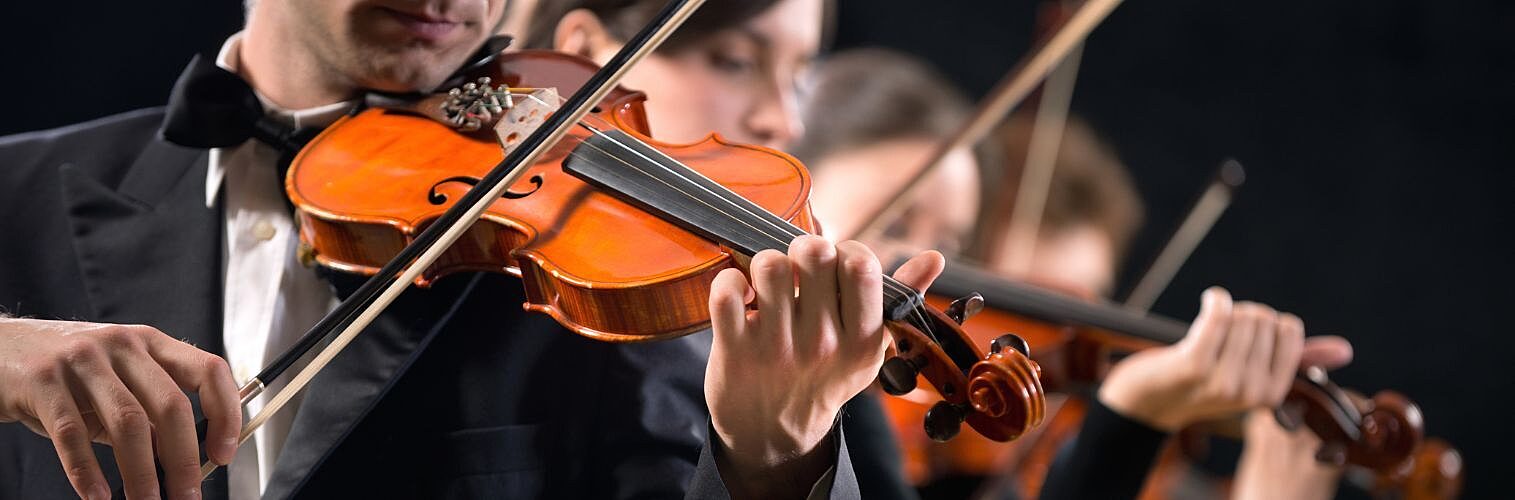 Violinists performing on stage on dark background.