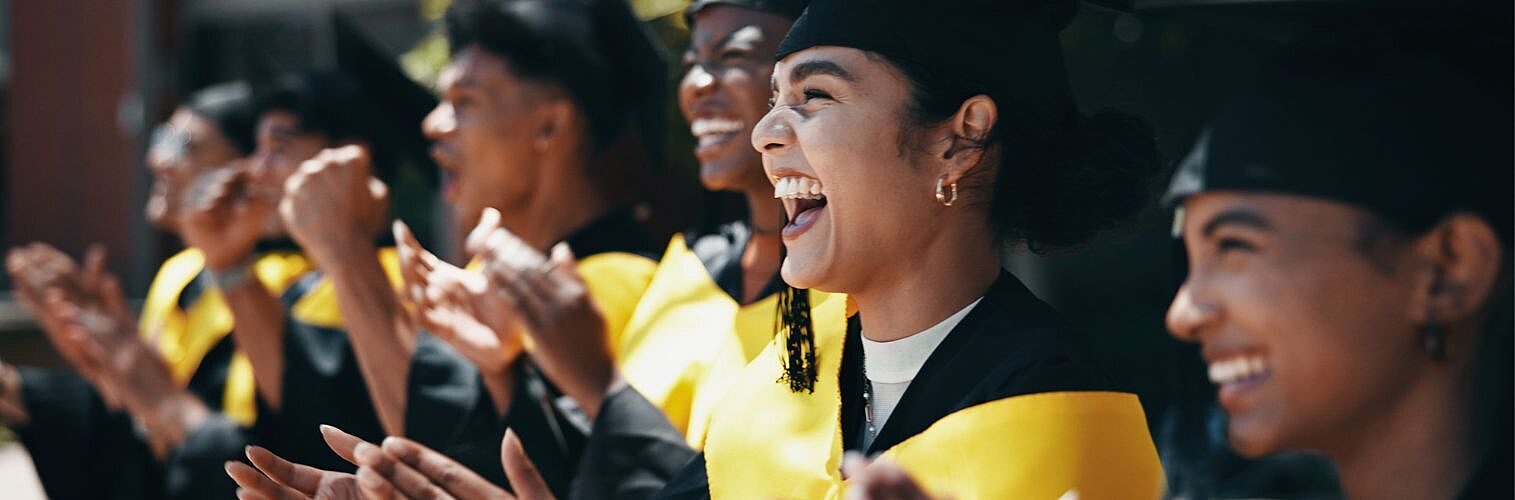 Excited students applaud at university graduation.