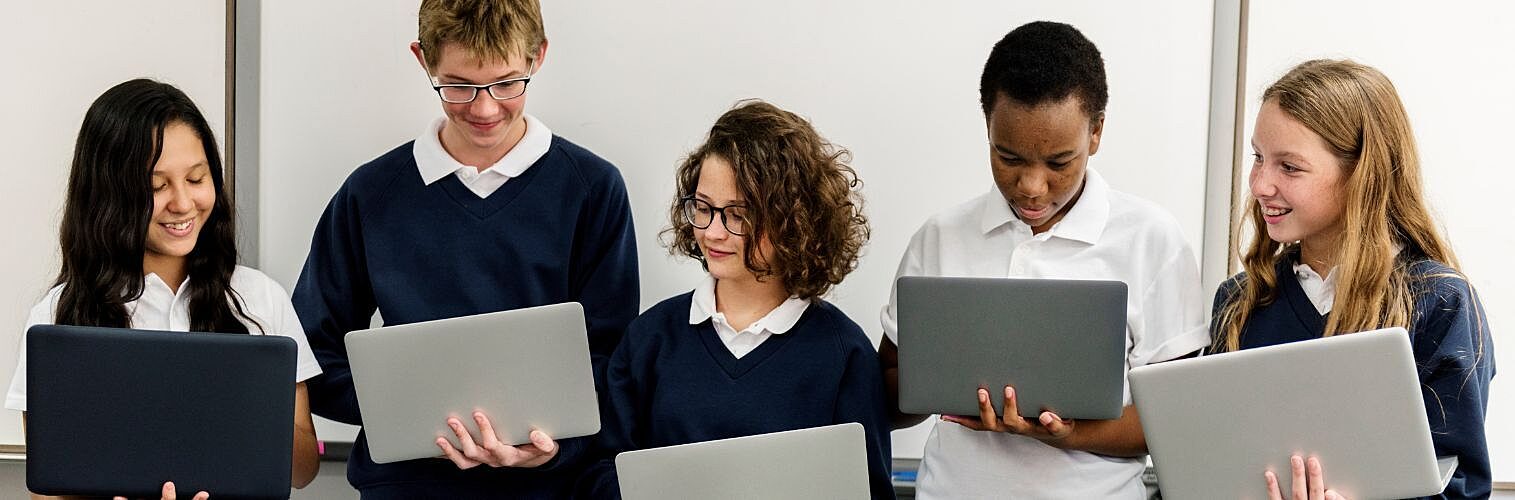 Secondary students using laptops in a modern classroom.