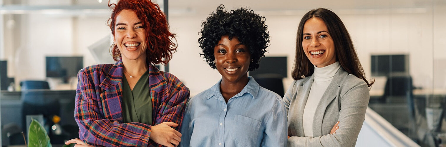 Multiracial women posing in the office while looking into the camera.