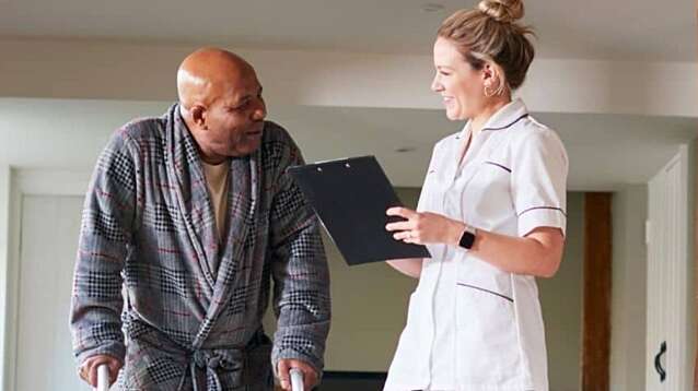 A man with a walking frame talking to a nurse