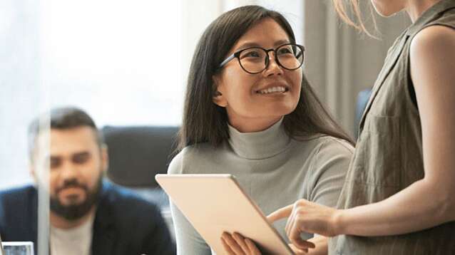 Two colleagues talking over an tablet at a desk