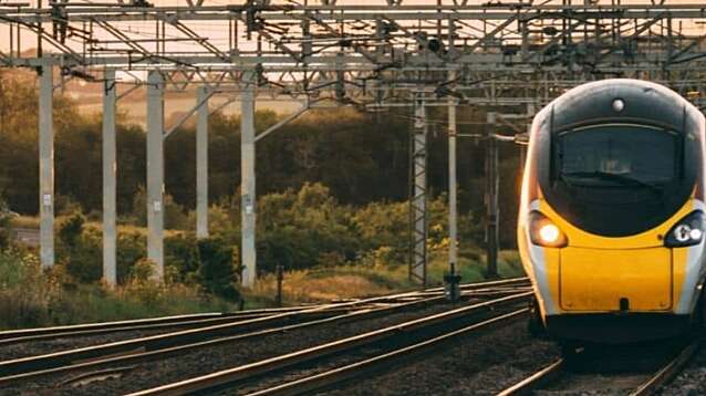 A train travelling down tracks with overhead lines above