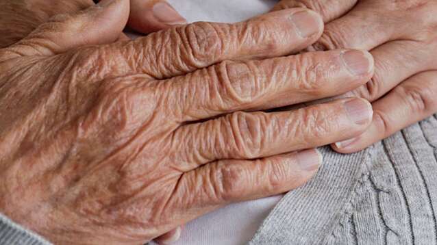 Young hands hugging an elderly person from behind.