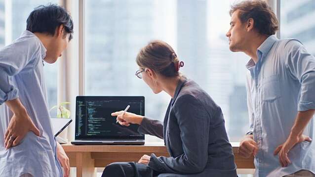 A team of consultants looking at a laptop screen full of code.