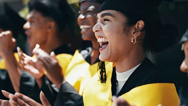 Excited students applaud at university graduation.