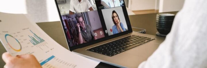 A person in a virtual meeting holding a sheet with data