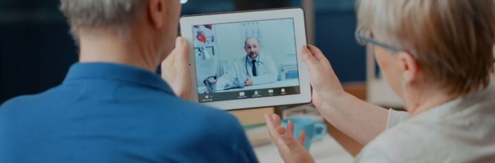 A senior couple consulting a doctor on a digital tablet.