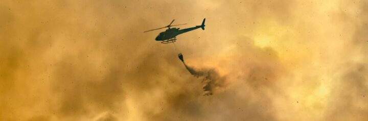 Helicopter dumping water on forest fire.