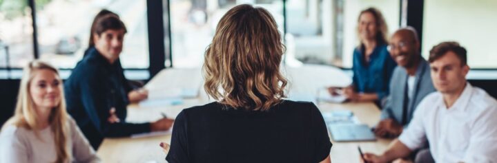 Rear view of a businesswoman addressing a meeting in office.