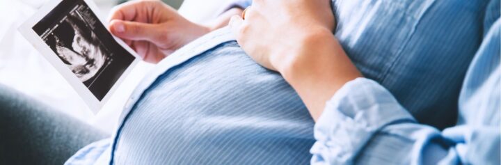 A pregnant woman looking at the photograph of an ultrasound.