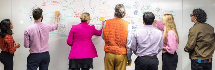 Nousers standing at a whiteboard.