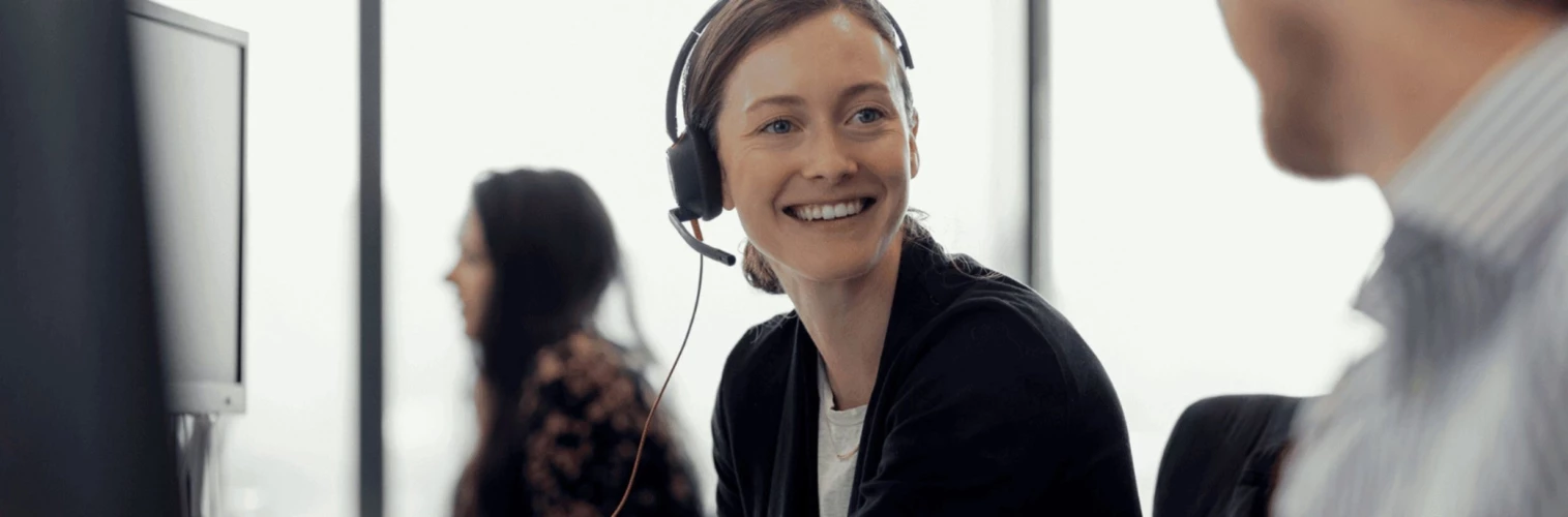 Woman sitting at a computer with a telephone headset on