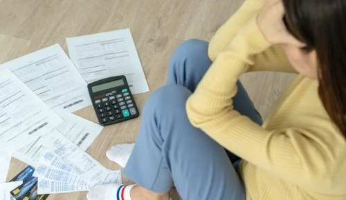 Woman looking over bills with calculator