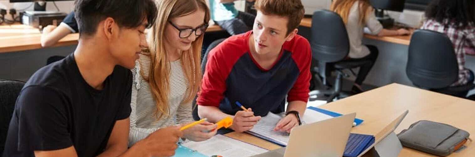 Three young people taking notes at a desk