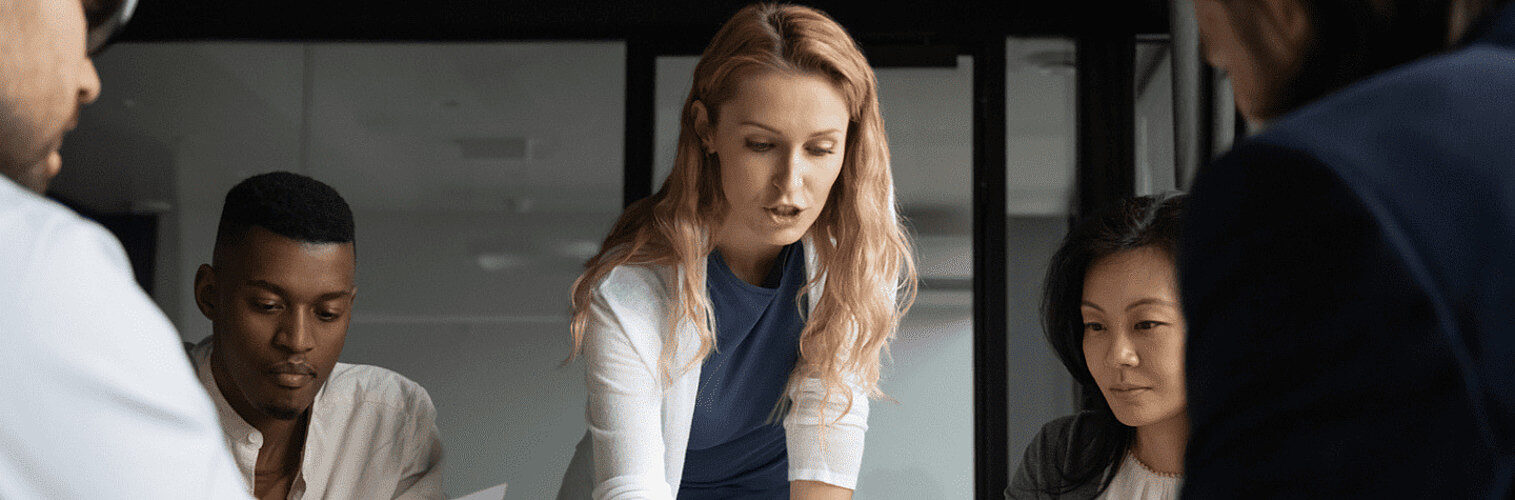 A woman gesturing toward a table in a meeting