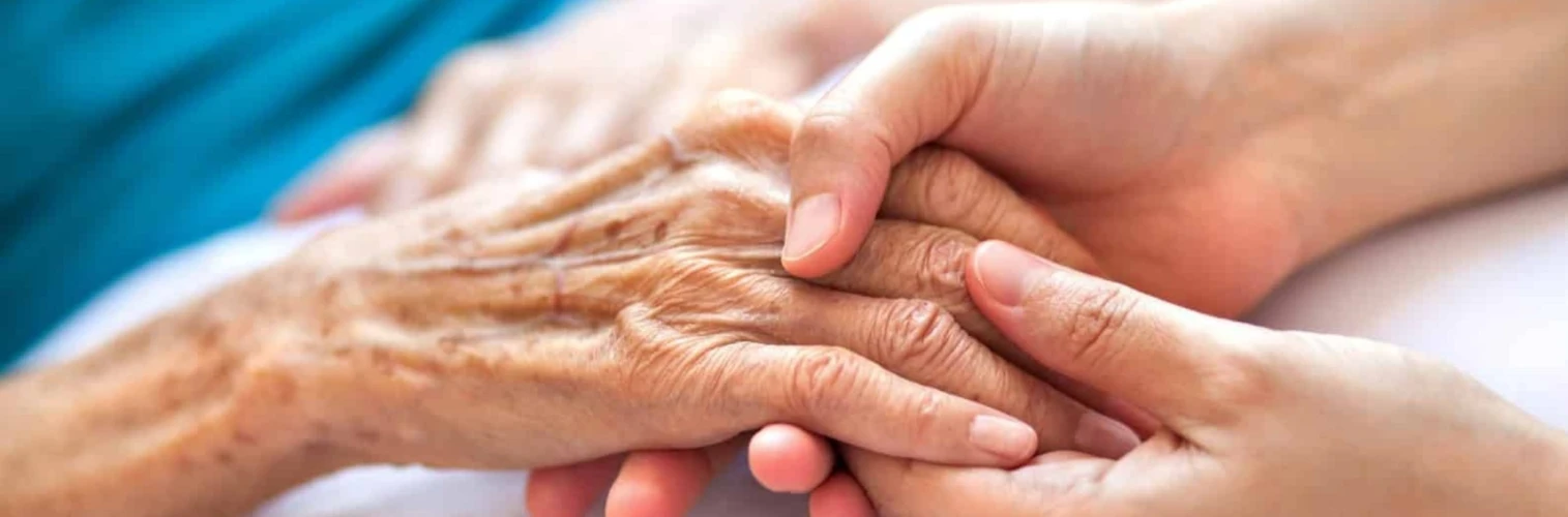 An elderly person's hand being held by a medical worker