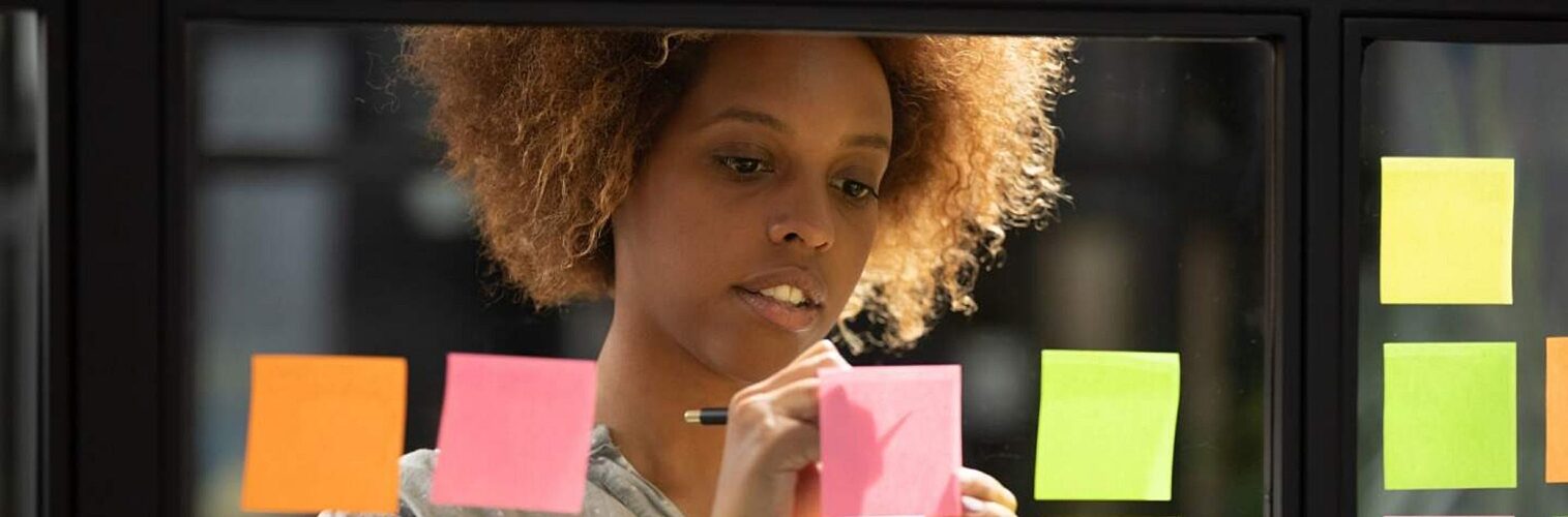 Woman of colour adding sticky notes to a whiteboard