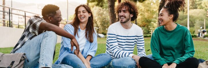 University students talking while sitting in a grassy outdoor area