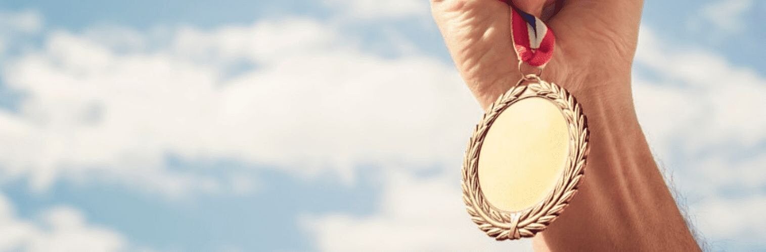 A hand holding up a gold medal