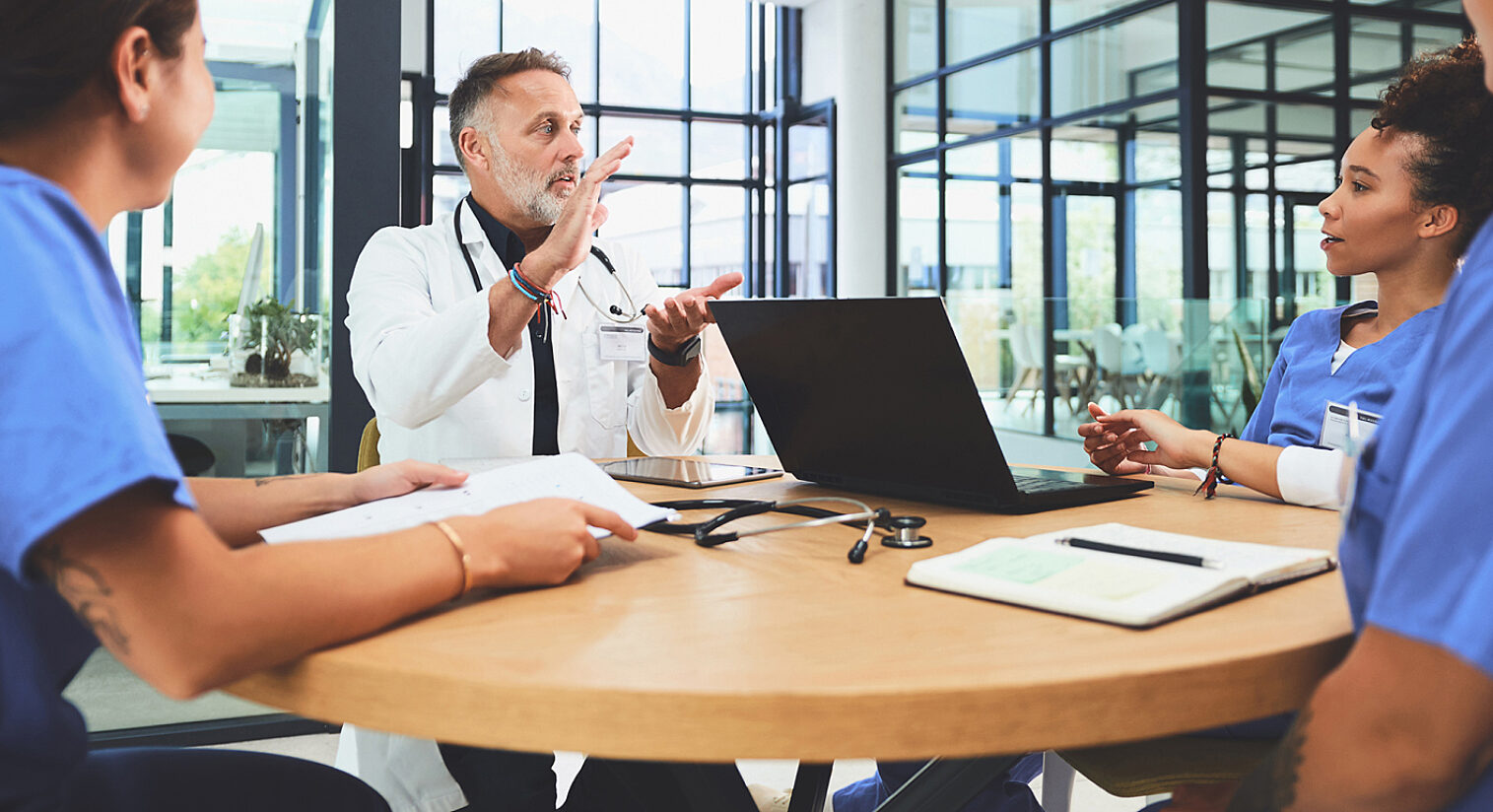 Four medical professionals sitting around a meeting room table